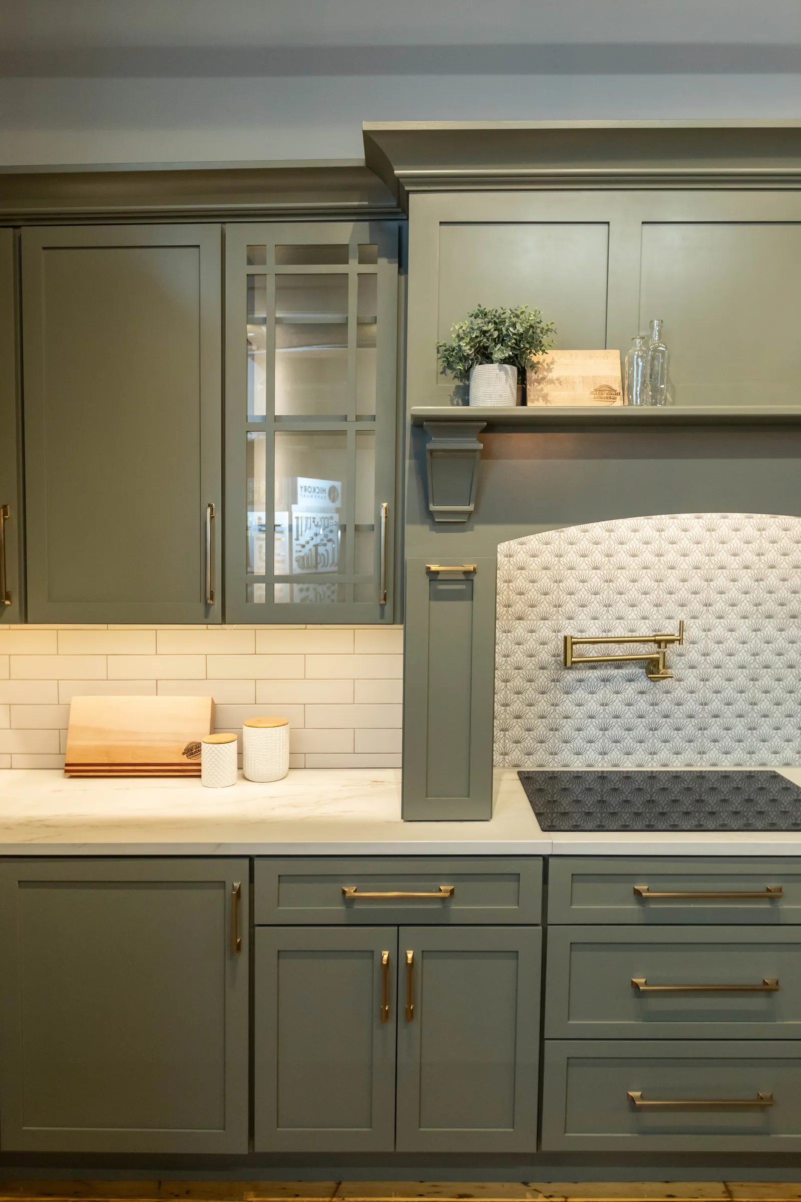 Sage cabinet detail with brass hardware and pot filler